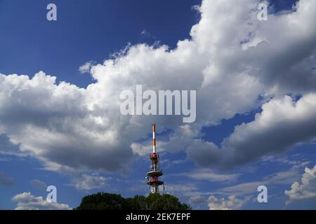 Alter Fernsehturm in Rot und Weiß unter majestätischen Wolken Stockfoto