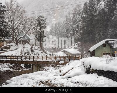 Eine Brücke über den Yokoyu River außerhalb des Jigokudani Monkey Park während eines Schneesturms. Stockfoto