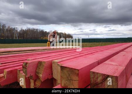 Kaluga, Russland 15. Oktober 2019: Bauarbeiten, ein Arbeiter malt Holzbalken mit einer speziellen Lösung. Neu Stockfoto