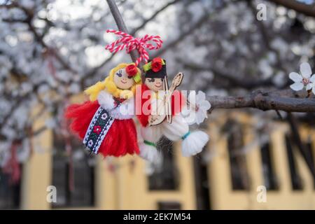 Rot-weiße Martenitsa oder Martison Armbänder, die an den Zweigen des blühenden Baumes hängen - bulgarische und rumänische Frühlingstradition Stockfoto