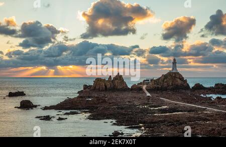 Straße zu La Corbiere Leuchtturm auf dem Meeresgrund bei Ebbe mit Klippe und Sonnenuntergang, Vogtei von Jersey, Kanalinseln Stockfoto