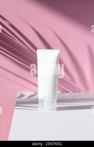 Flasche Creme mit Palmblatt Schatten auf rosa Hintergrund Stockfoto