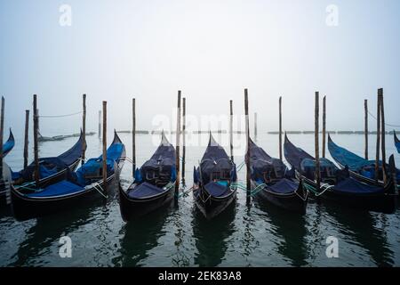 Venedig, Italien. 23rd. Februar 2020. Gondeln werden vor dem Ducale Palace vertäut, während die Stadt am 23. Februar 2021 in Venedig, Italien, in dichten Nebel getaucht ist. © Simone Padovani / Behind Venice / Alamy Live News Stockfoto