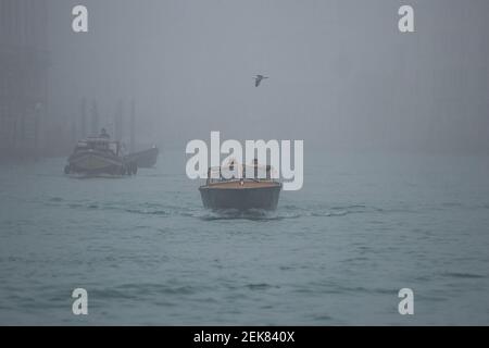 Venedig, Italien. 23rd. Februar 2020. Ein Boot fährt den Canal Grande, während die Stadt am 23. Februar 2021 in Venedig, Italien, in dichten Nebel getaucht ist. © Simone Padovani / Behind Venice / Alamy Live News Stockfoto