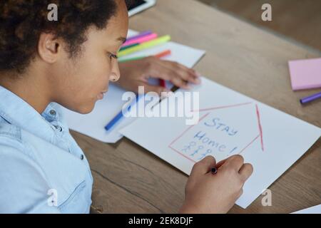 Porträt von gemischten Rennen teen Schulmädchen Zeichnung Aufenthalt Home Inschrift Auf Papier mit bunten Markern, während Sie Zeit zu Hause verbringen Während der Quarantäne Stockfoto