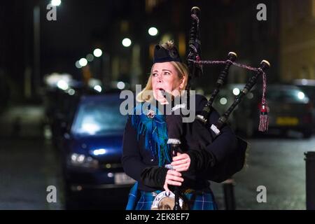 Piper Louise Marshall spielt auf ihren Dudelsäcken, und Nachbarn auf der Straße in Leith stehen in ihren Türen, um für Heldenhund zu klatschen. Dies ist auf eine nationale Sperre von 3rd bezüglich eines mutierten Stammes von covid-19 zurückzuführen. Kredit: Euan Cherry Stockfoto