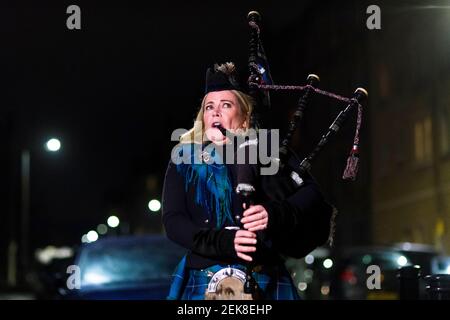 Piper Louise Marshall spielt auf ihren Dudelsäcken, und Nachbarn auf der Straße in Leith stehen in ihren Türen, um für Heldenhund zu klatschen. Dies ist auf eine nationale Sperre von 3rd bezüglich eines mutierten Stammes von covid-19 zurückzuführen. Kredit: Euan Cherry Stockfoto