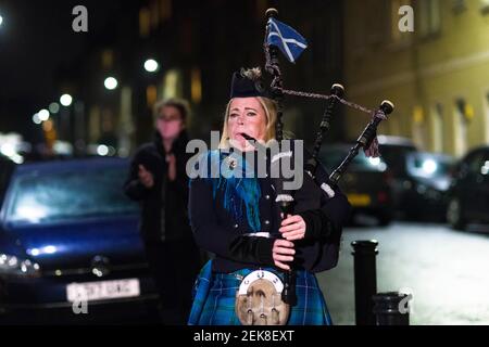 Piper Louise Marshall spielt auf ihren Dudelsäcken, und Nachbarn auf der Straße in Leith stehen in ihren Türen, um für Heldenhund zu klatschen. Dies ist auf eine nationale Sperre von 3rd bezüglich eines mutierten Stammes von covid-19 zurückzuführen. Kredit: Euan Cherry Stockfoto