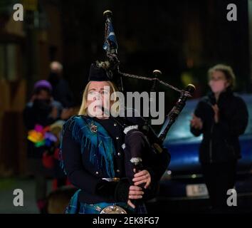 Piper Louise Marshall spielt auf ihren Dudelsäcken, und Nachbarn auf der Straße in Leith stehen in ihren Türen, um für Heldenhund zu klatschen. Dies ist auf eine nationale Sperre von 3rd bezüglich eines mutierten Stammes von covid-19 zurückzuführen. Kredit: Euan Cherry Stockfoto