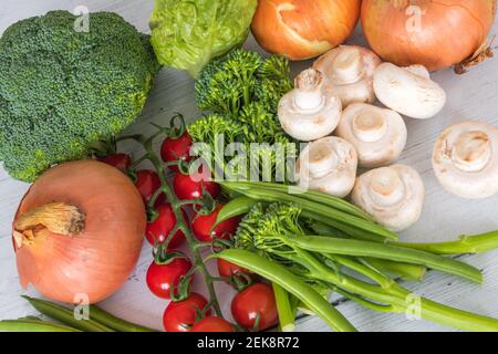 Tenderstem Broccoli, Tomaten, grüne Bohnen Zwiebeln Salat Broccoli Pilze auf einem weiß bemalten Brett aus dem Wintergarten ausgelegt. Stockfoto