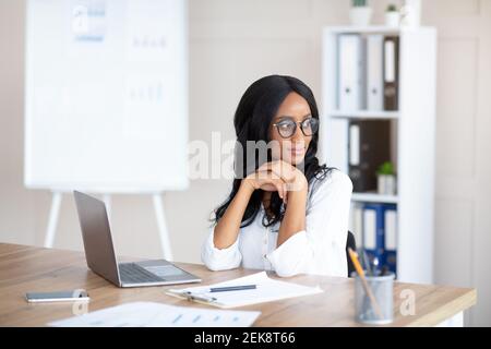 Porträt einer jungen Sekretärin beim Tagträumen vor dem Laptop am Arbeitsplatz, Platz zum Kopieren Stockfoto