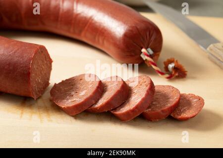 Scheiben traditioneller türkischer Halal-Sucuk, eine trockene, würzige und fermentierte Wurst aus nächster Nähe auf einem Schneidebrett Stockfoto