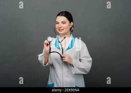 Schöne Ärztin in Schutzmaske wegschauen und über etwas nachdenken. Stockfoto