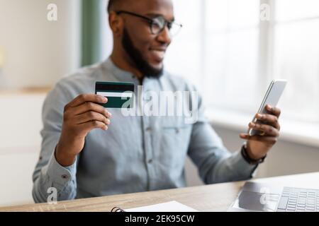 Schwarzer Geschäftsmann Mit Kreditkarte Und Smartphone Sitzen Im Büro Stockfoto