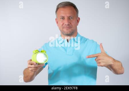 Junger Mann mit Wecker auf weißem Hintergrund. Stockfoto
