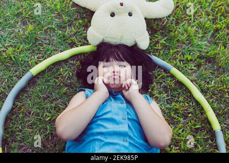 Kind mit Teddybär liegt auf dem Rasen Stockfoto