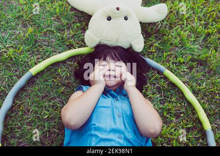 Kind mit Teddybär liegt auf dem Rasen Stockfoto