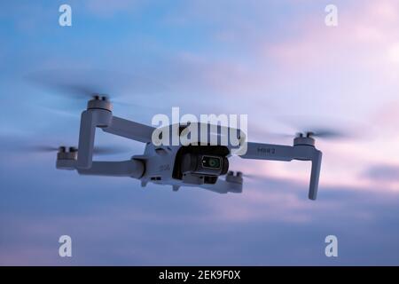 Kharkiv, Ukraine - 21. Februar 2021: DJI Mavic Mini 2 Drohne fliegt im Sonnenuntergang Himmel mit leuchtend violetten Wolken. Neue Quadcopter Gerät schwebt in der Luft Stockfoto