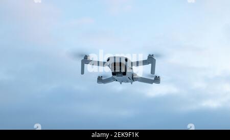 Kharkiv, Ukraine - 21. Februar 2021: DJI Mavic Mini 2 Drohne fliegt in den Himmel mit Wolken. Neue Quadcopter Gerät schwebt auf bewölktem pastellfarbenen Himmel Hintergrund Stockfoto