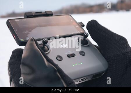 Kharkiv, Ukraine - 21. Februar 2021: DJI Mavic Mini 2 (dji Air 2) Drohne Fernbedienung in den Händen in Winterhandschuhen mit angeschlossenem Telefon. Bedienung von drone Stockfoto