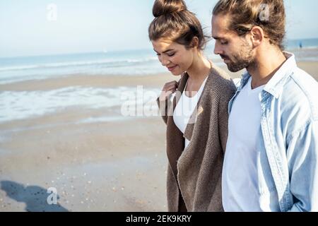 Junges Paar, das an sonnigen Tagen am Strand spazieren geht Stockfoto