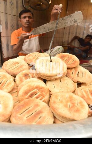 Dhaka. Februar 2021, 23rd. Ein Mann macht Bakorkhani in einem Geschäft in Dhaka, Bangladesch, 23. Februar 2021. Bakorkhani, ein rundes knuspriges Fladenbrot, wird hauptsächlich aus Mehl, Milch, Salz, Käse und süßen Zutaten hergestellt. Es ist ein gemeinsames Frühstück Snack in der Stadt. Quelle: Xinhua/Alamy Live News Stockfoto