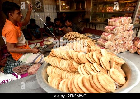 Dhaka. Februar 2021, 23rd. Ein Mann macht Bakorkhani in einem Geschäft in Dhaka, Bangladesch, 23. Februar 2021. Bakorkhani, ein rundes knuspriges Fladenbrot, wird hauptsächlich aus Mehl, Milch, Salz, Käse und süßen Zutaten hergestellt. Es ist ein gemeinsames Frühstück Snack in der Stadt. Quelle: Xinhua/Alamy Live News Stockfoto