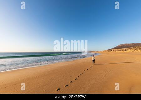 Klarer Himmel über Frau, die alleine am Greenly Beach entlang geht Stockfoto