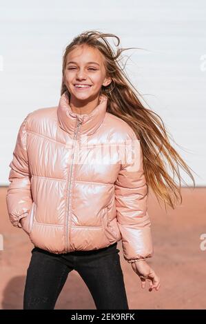 Lächelndes Mädchen mit der Hand in der Tasche, die gegen die Wand steht Stockfoto