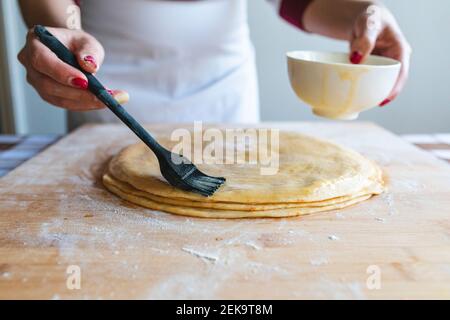 Frau Anwendung Ei auf Teig mit Gießbürste zu machen Croissants in der Küche Stockfoto