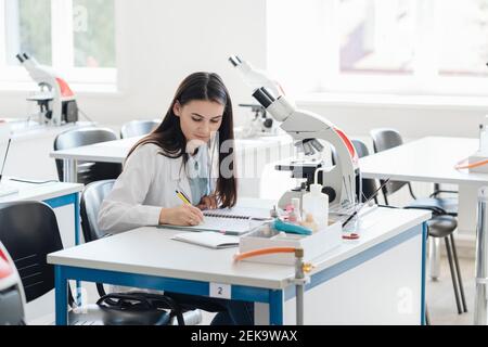 Junge Forscher im weißen Mantel Notizen in der Wissenschaft Klasse Stockfoto