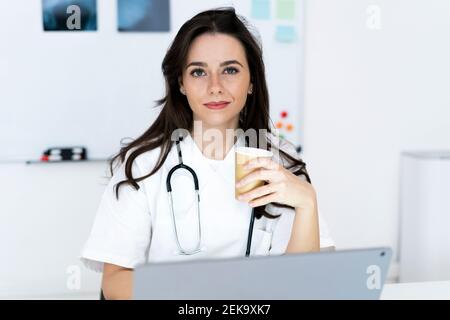 Lächelnd selbstbewusste Ärztin mit Kaffeetasse in der Klinik Stockfoto