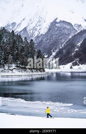 Mann beim Skifahren am schneebedeckten Seeufer Stockfoto