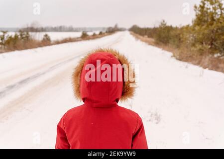 Junge trägt roten Wintermantel auf verschneite Landschaft stehen Stockfoto