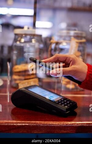 Frau mit Handy für die Zahlung im Café Stockfoto
