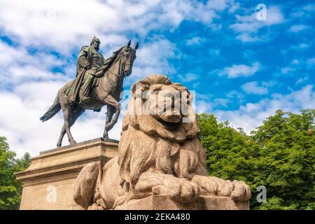 Deutschland, Baden-Württemberg, Stuttgart, Löwe ruht zu Füßen der Reiterstatue von Kaiser Wilhelm I. am Karlsplatz Stockfoto