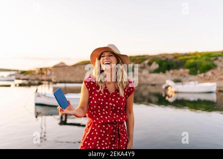 Reife Frau hält Handy, während sie gegen den Himmel steht Stockfoto