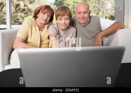 Junge sitzt mit seinen Großeltern mit einem Laptop Stockfoto