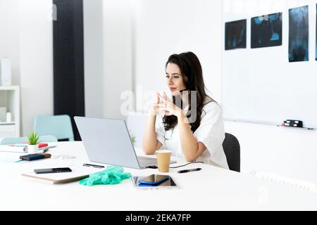 Ärztin in Online-Beratung durch Laptop am Schreibtisch Stockfoto