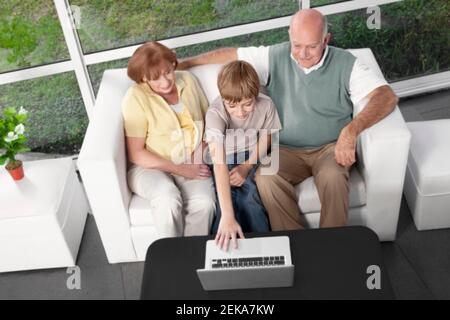 Junge sitzt mit seinen Großeltern mit einem Laptop Stockfoto
