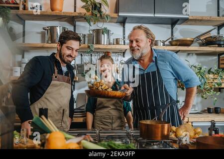 Reifer Koch, der King Austernpilze in der Bratpfanne rührt Stehen bei Kollegen in der Küche Stockfoto