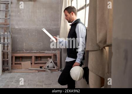 Männlicher Auftragnehmer, der das Dokument im Gebäude auswertet Stockfoto