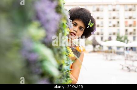 Junge Frau versteckt sich hinter Pflanze Stockfoto