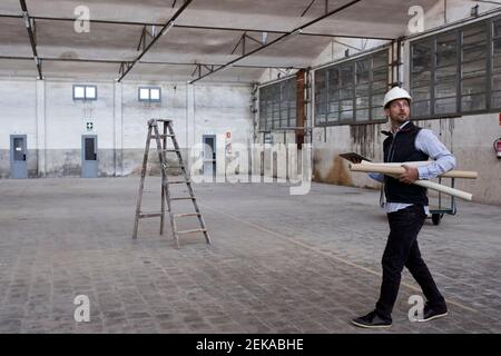 Männlicher Architekt mit Kartons, die im Gebäude auf dem Boden herumlaufen Stockfoto