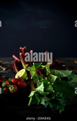 Studio Schuss von frischen Rhabarber Stiele, Erdbeeren und halbierte Limette Stockfoto