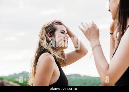 Schöne junge Frau mit Hand im Haar Blick auf Frau Freund Stockfoto