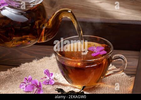 Gießt Kräutertee aus Feuerkraut in eine transparente Tasse. Stockfoto