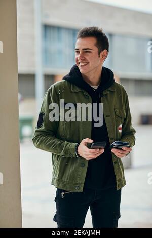 Lächelnder, hübscher Mann mit Mobiltelefon, das die Kreditkarte hält Wegschauen Stockfoto