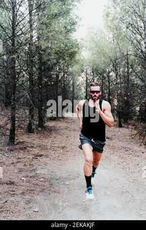 Schöner männlicher Athlet, der auf dem Bergpfad im Wald läuft Stockfoto