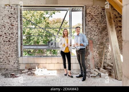 Geschäftsfrau, die auf der Baustelle mit einem Kollegen diskutiert Stockfoto